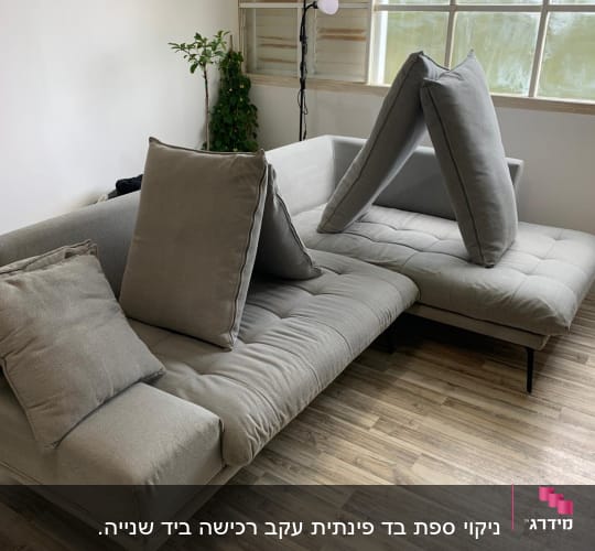 ספה אפורה עם כריות בחדר מואר